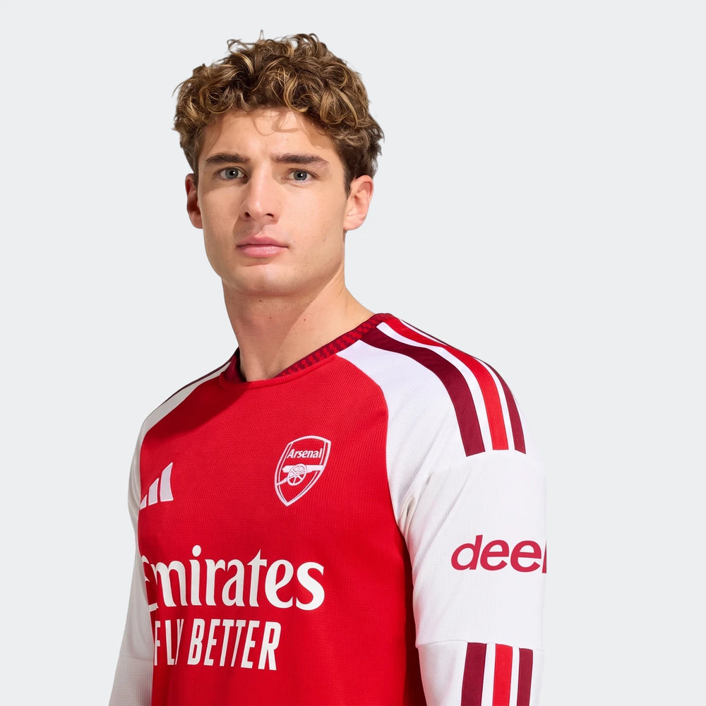 A male model wears the red and white Arsenal FC 26/27 Home Long Sleeve Jersey, featuring the club crest and sponsor logos.
