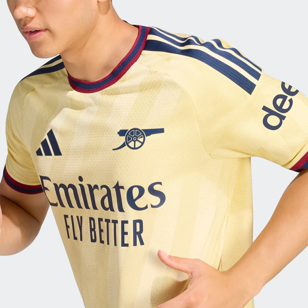 Close-up of a person wearing the yellow Arsenal Fc 26/27 Third Authentic Jersey with navy and red details.