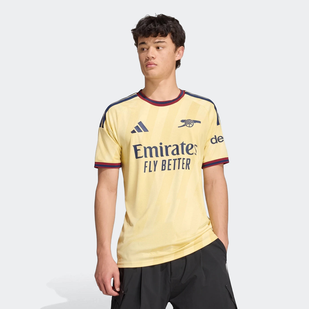 Male model wearing the light yellow Arsenal FC 26/27 Third Jersey, featuring dark blue branding and red trim.