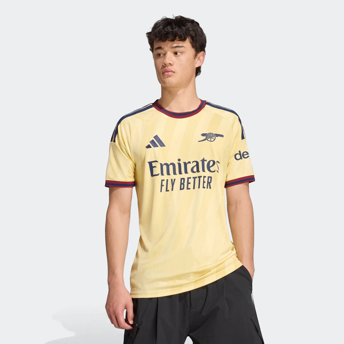 Male model wearing the light yellow Arsenal FC 26/27 Third Jersey, featuring dark blue branding and red trim.