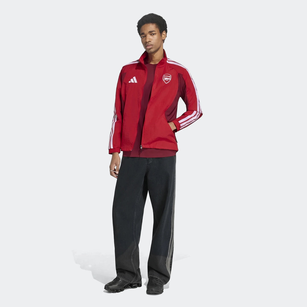 Arsenal Fc Home Anthem Jacket worn by a model, featuring a red main body with white stripes and team crest, paired with dark