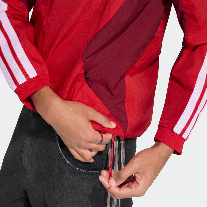 Close-up of a person's hands adjusting the drawstring of a red Arsenal Fc Home Anthem Jacket with white stripes on a sleeve.