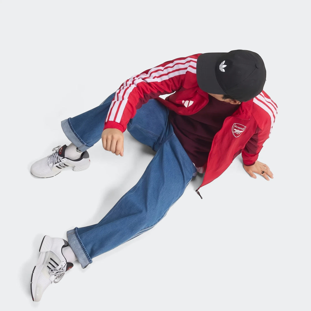 Arsenal FC Home Anthem Jacket in red with white sleeve stripes, zip front and Arsenal crest, worn in side view.
