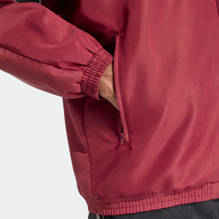 Arsenal Fc Street Track Top in burgundy fabric, close-up of elastic cuff sleeve and zippered side pocket