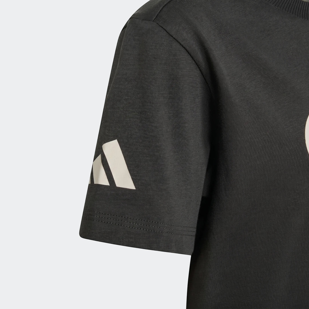 Close-up of a Kids' Audi Revolut F1 Team DNA Graphic T-Shirt in dark gray, showing the white logo on the short sleeve.