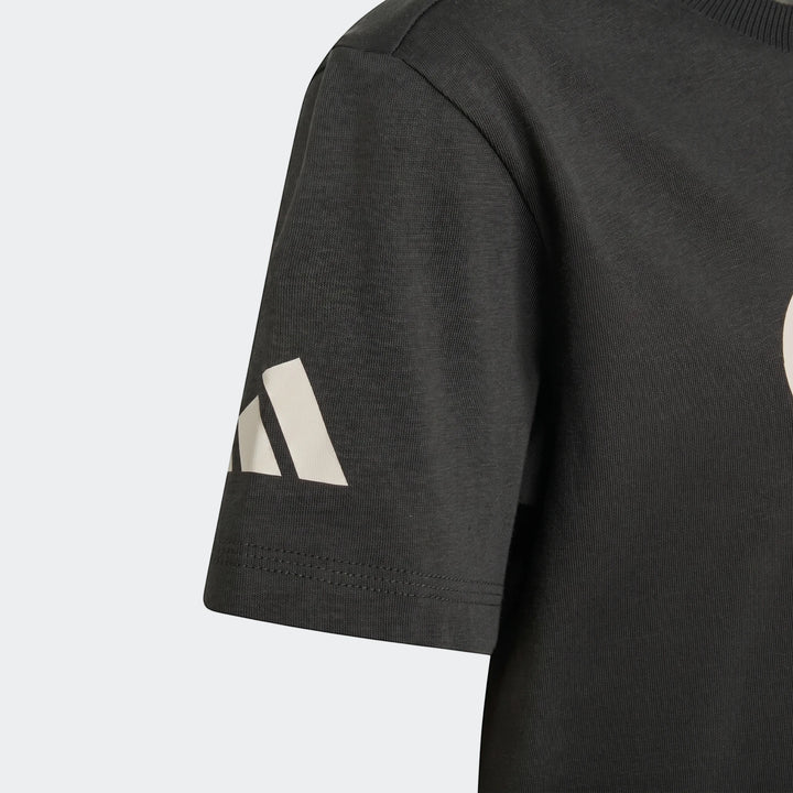 Close-up of a Kids' Audi Revolut F1 Team DNA Graphic T-Shirt in dark gray, showing the white logo on the short sleeve.
