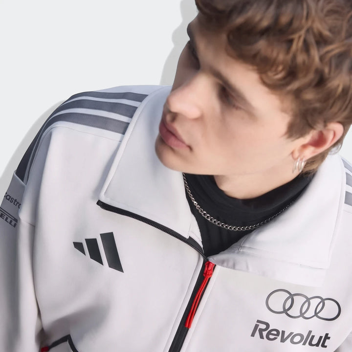 Close-up of a male model wearing a white Audi Revolut F1 Team Engineers & Marketing Track Top with sponsor logos.