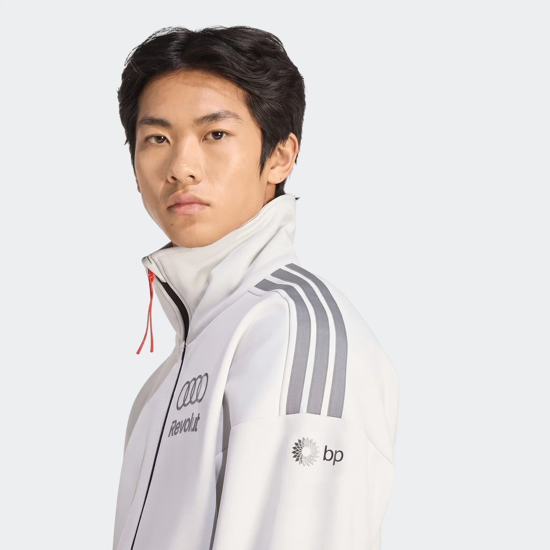 Young man wearing an official white Audi Revolut F1 Team Engineers & Marketing Track Top, featuring sponsorship logos.