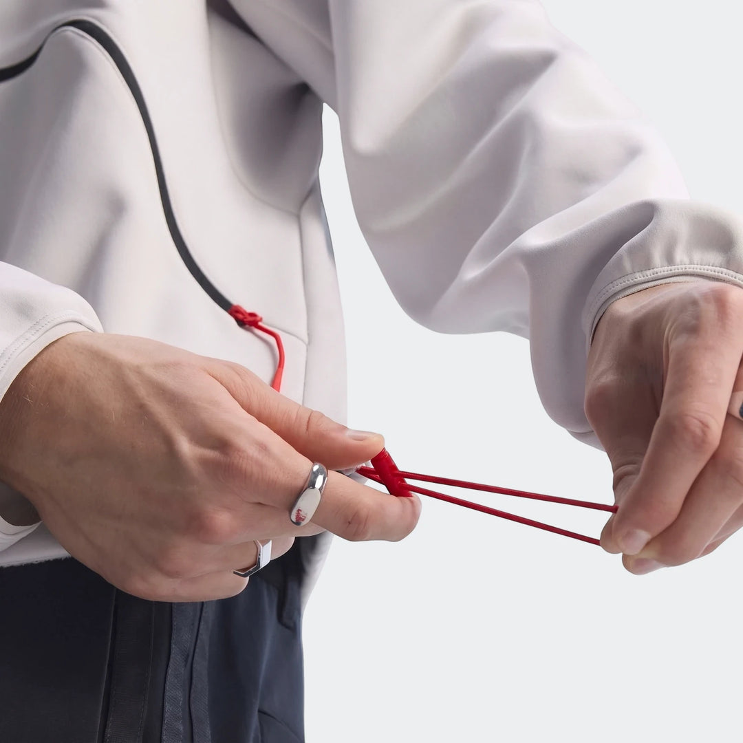 White Audi Revolut F1 Team Engineers & Marketing Track Top being adjusted by hands, showing red drawstrings and silver rings.