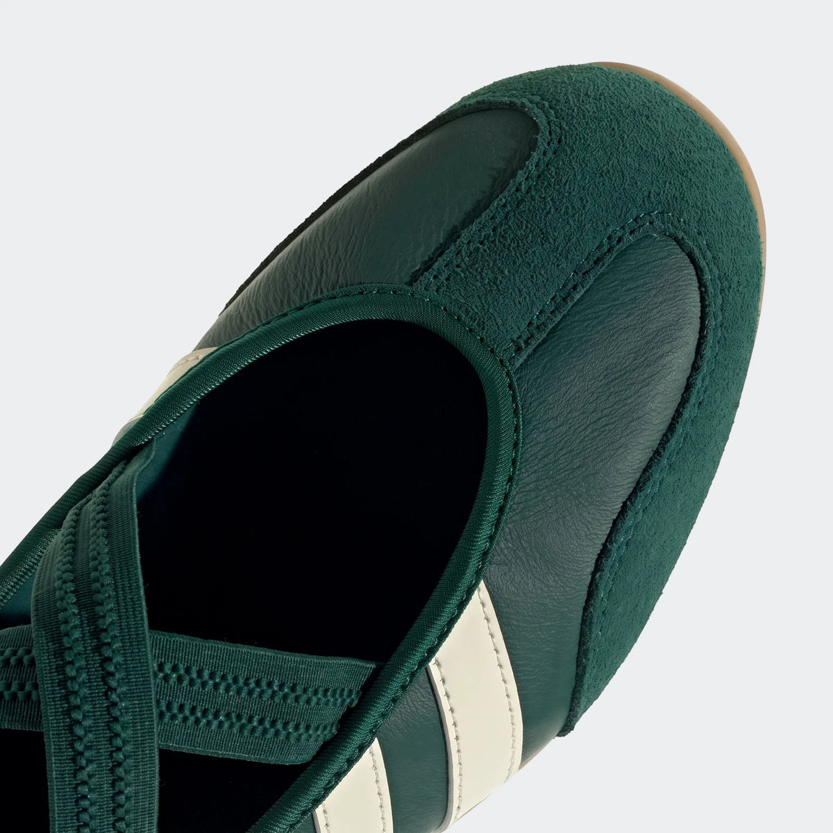Close-up view of a dark green Barreda Mary Jane shoe with white stripes and elastic straps, featuring leather and suede