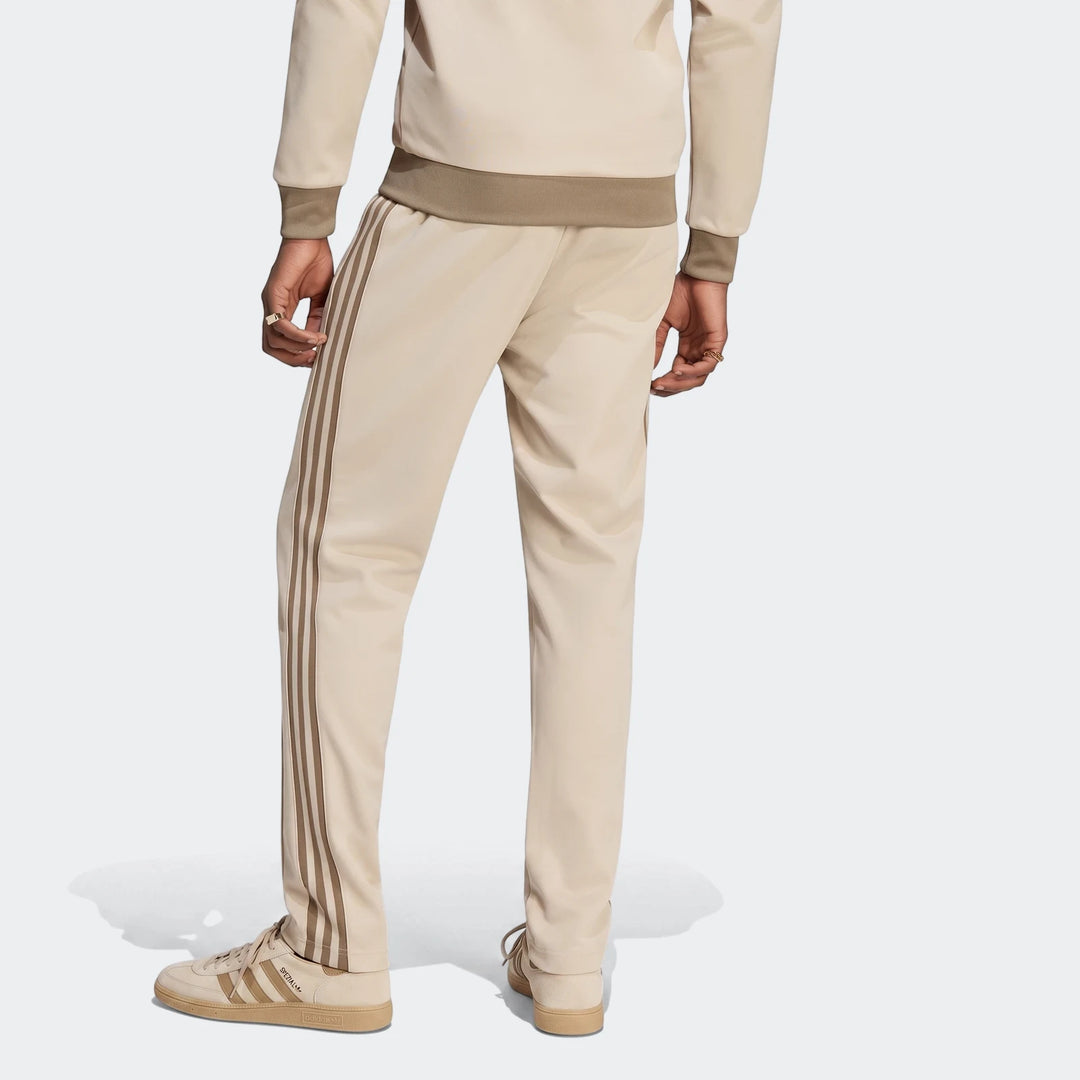 Beige Adidas Classic Track Pants with three stripes worn by a model, viewed from the back.