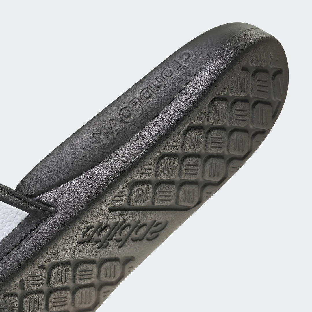 Close-up of a black Adidas Adilette slide sandal sole, featuring embossed brand logos and a distinctive textured pattern.