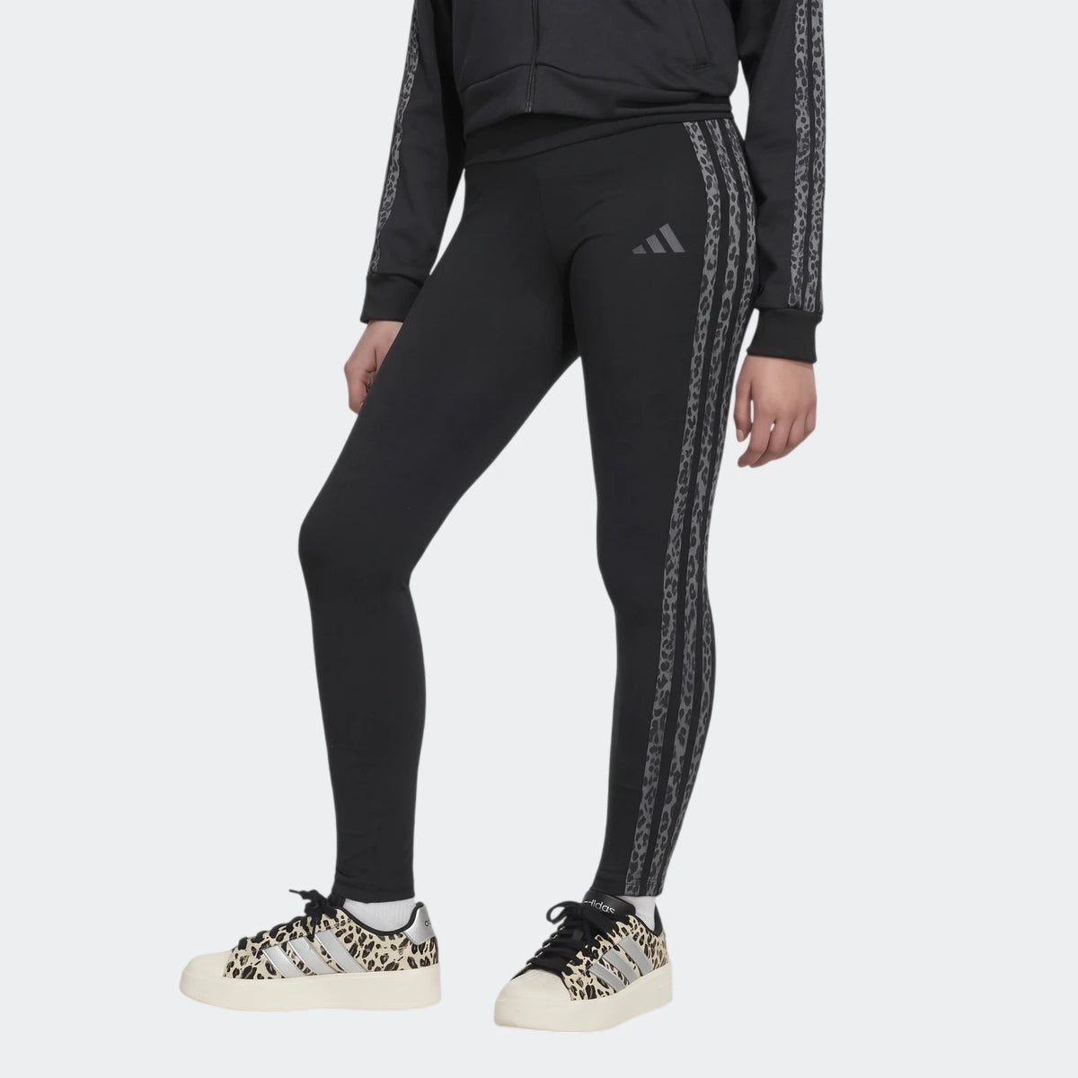 Close-up of a person wearing black Adidas Animal Leggings with leopard print stripes and matching leopard print platform