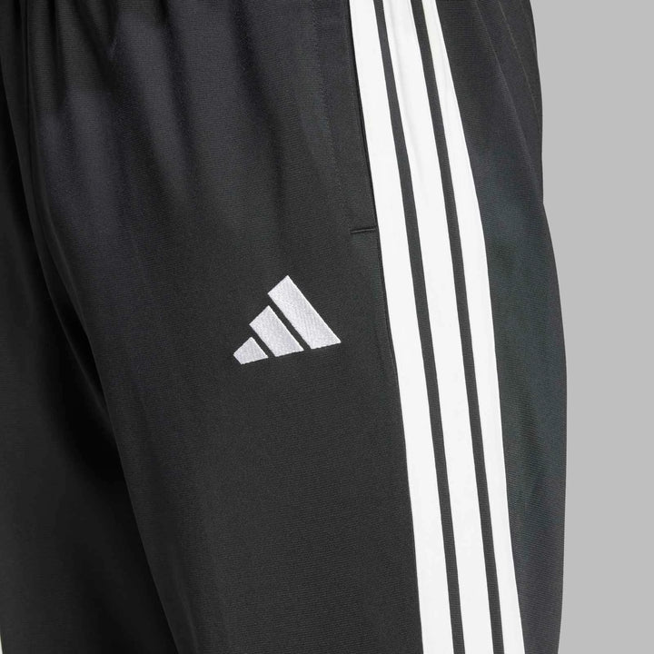 Close-up of black Adidas Dayready Tracksuit pants, featuring prominent white three-stripe design and embroidered logo.