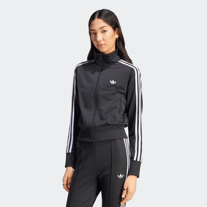 Black Adidas Firebird Classic Track Jacket worn by a woman, paired with matching track pants, full zipper front.