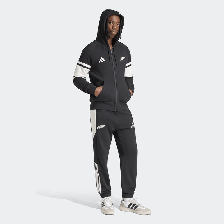Black Adidas New Zealand Rugby Leisurewear Full Zip Hoodie and matching track pants worn by a male model, front view.