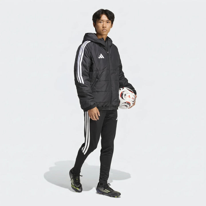 Male model in black Adidas Tiro 26 Windbreaker Jacket and track pants, holding a soccer ball, full body shot.