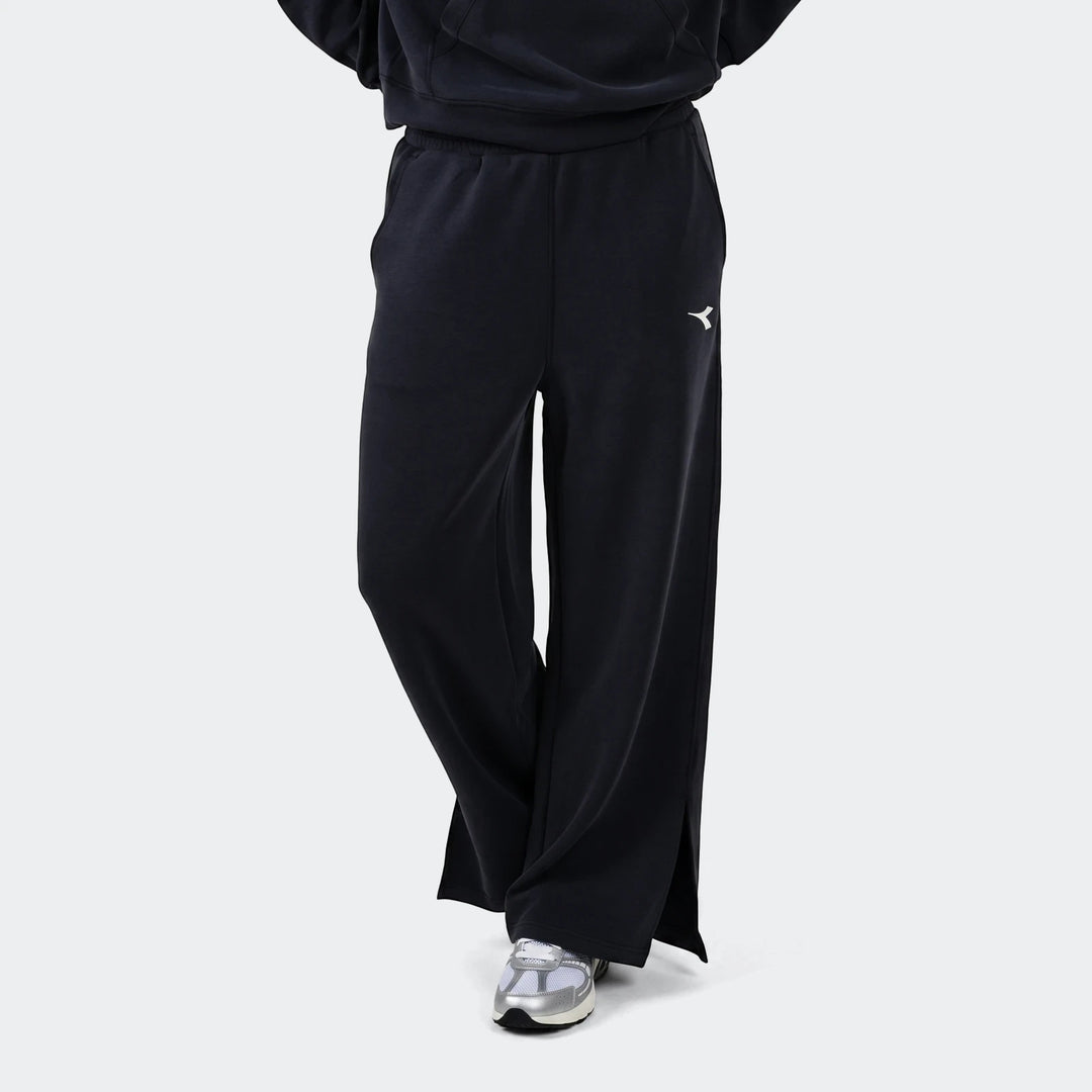 Black Diadora Danielle Trackpant worn by a model, featuring a wide-leg design and white Diadora logo on the thigh.