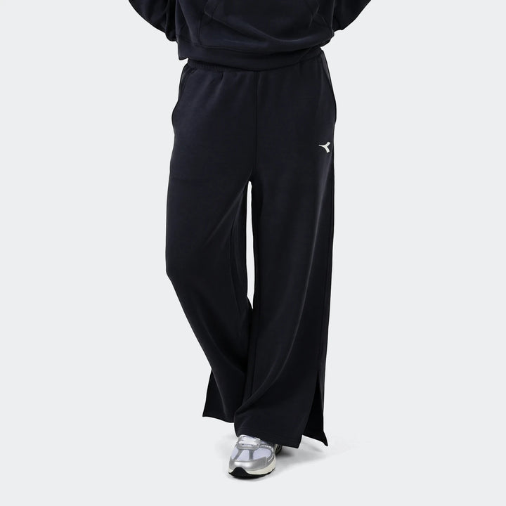 Black Diadora Danielle Trackpant worn by a model, featuring a wide-leg design and white Diadora logo on the thigh.