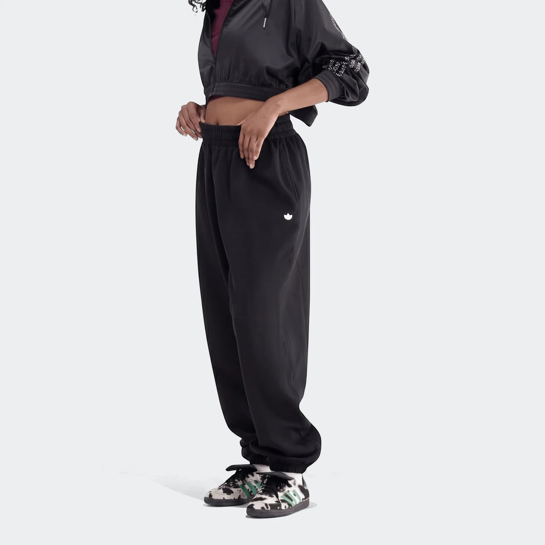 Black Essentials French Terry Jogger Pants worn by a person, paired with a black cropped jacket and patterned sneakers.
