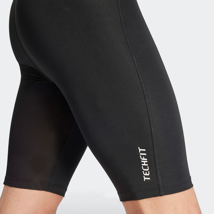 Close-up of black football base layer compression short tights with a TECHFIT logo on a model's legs.