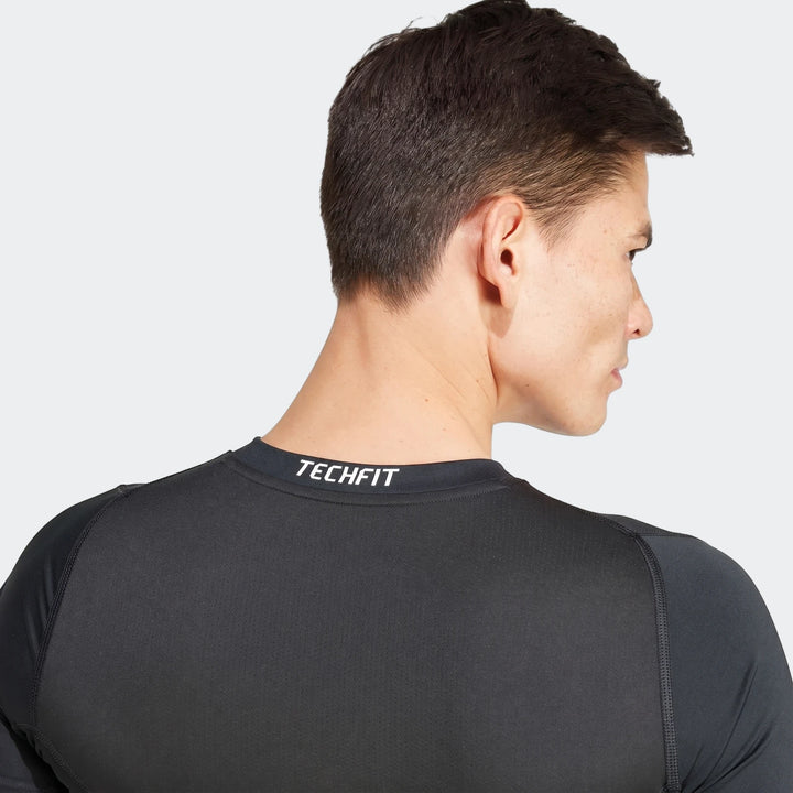 Man wearing a black Techfit long-sleeve football t-shirt, shown from the back and side view, highlighting the shirt's fit