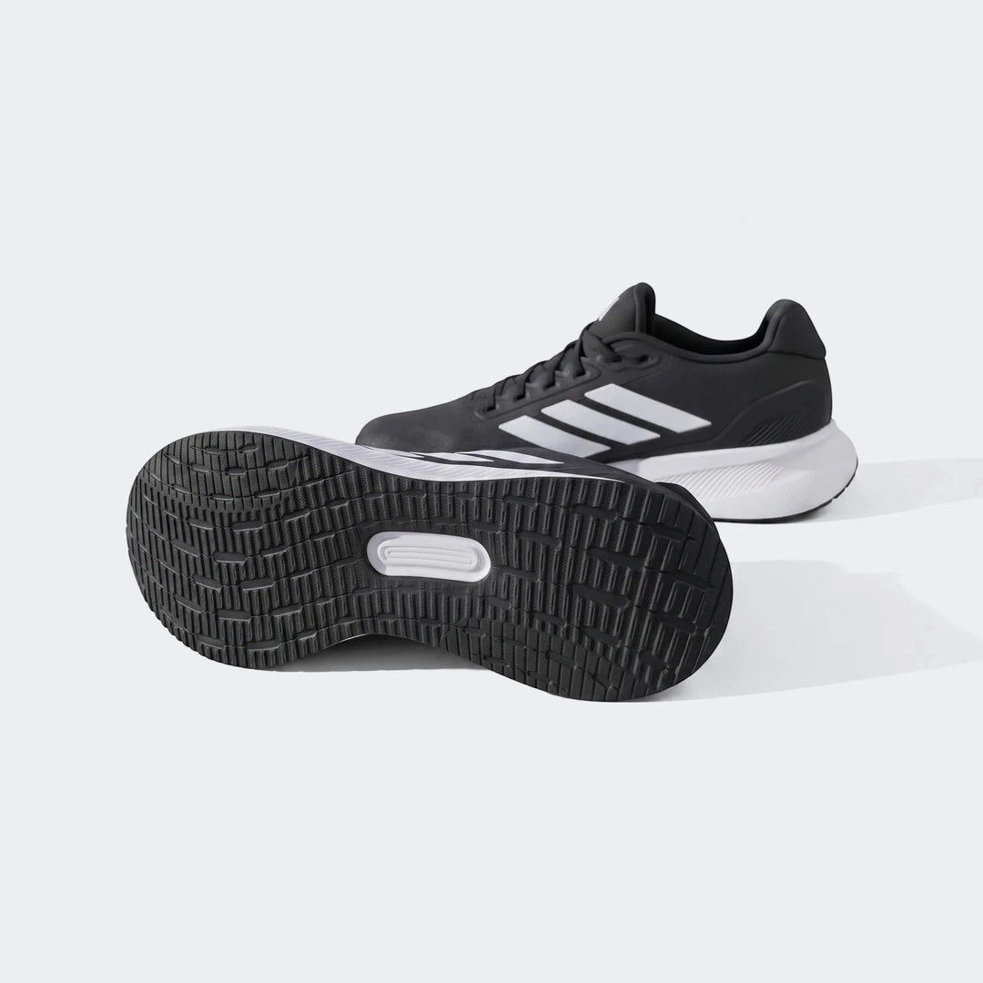 Black and white Adidas running shoes, showcasing the textured outsole and prominent three-stripe logo on an outdoor trail.