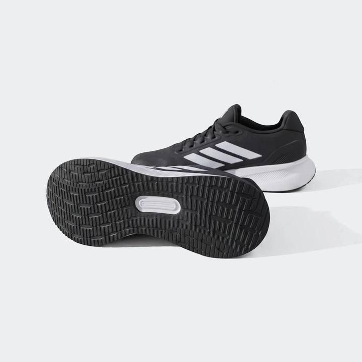 Black and white Adidas running shoes, showcasing the textured outsole and prominent three-stripe logo on an outdoor trail.