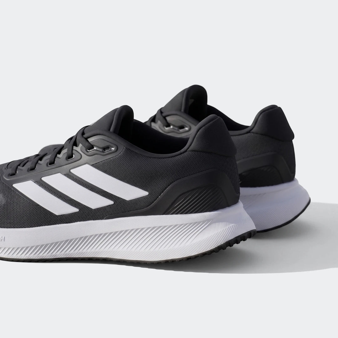 Pair of black and white Adidas running shoes, featuring the iconic three stripes, viewed from a rear-quarter angle on an