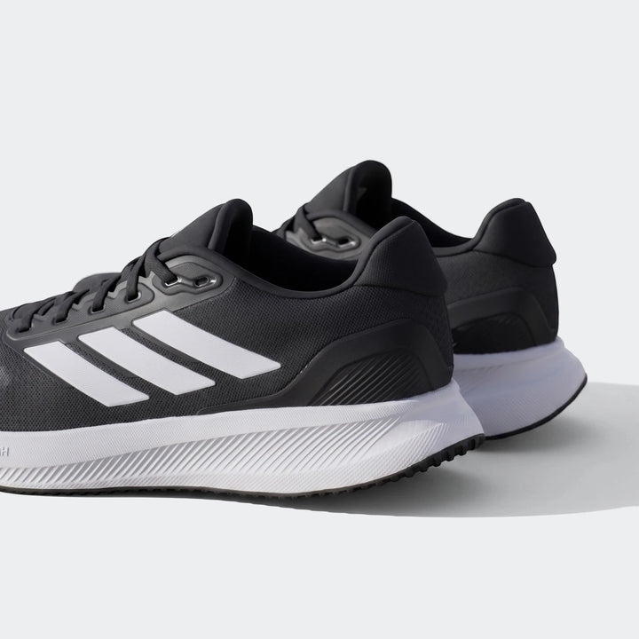 Pair of black and white Adidas running shoes, featuring the iconic three stripes, viewed from a rear-quarter angle on an