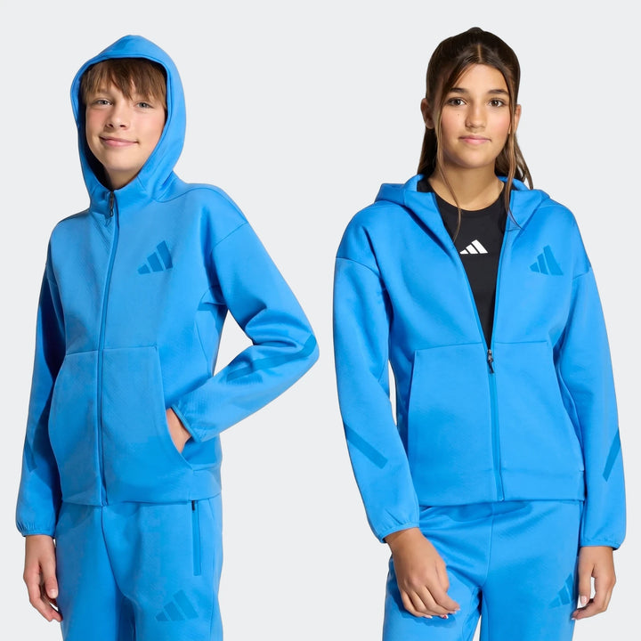 Two youth models, a boy and a girl, wearing blue adidas Youth Z.N.E. Full-Zip Hoodies and matching sweatpants, front view.