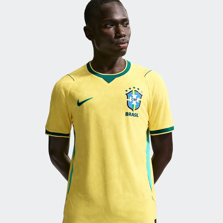 Male model wearing a yellow Brazil National Team 2026 Match Home Nike Aero-Fit soccer jersey with green trim and team crest.