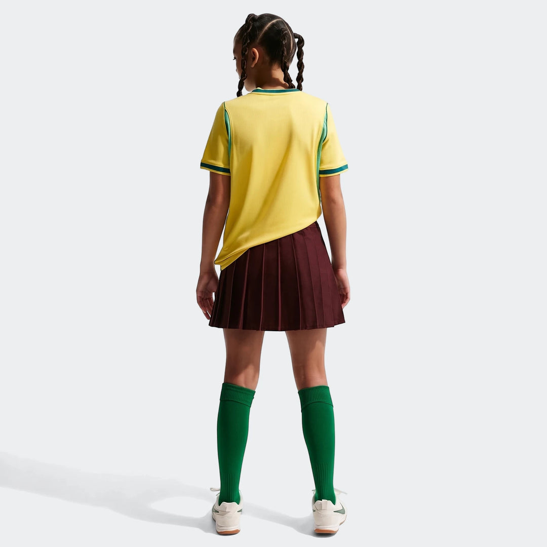 Rear view of a young person wearing a yellow Brazil National Team 2026 Stadium Home Nike Dri-Fit soccer jersey and maroon