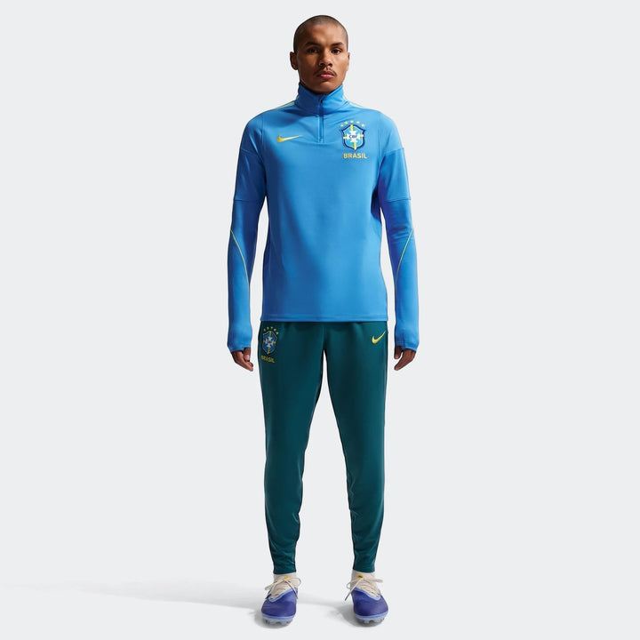 Men's Brazil Strike Nike Dri-FIT blue long-sleeve soccer drill top and green athletic pants on a model, front view.