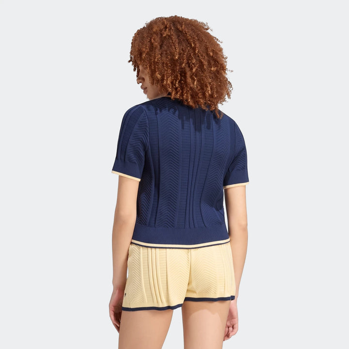 Woman wearing a navy Cable Knit Cali Tee Polo with cream trim and matching yellow shorts, captured from the back.