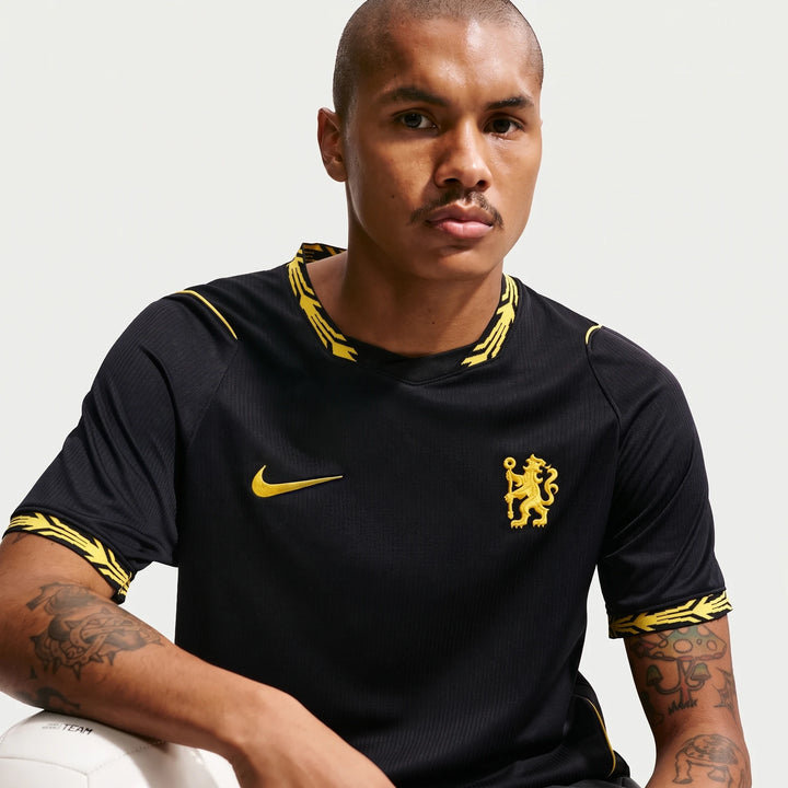 Man wearing a black Chelsea FC 2026/27 Stadium Away Nike Dri-Fit Soccer Replica Jersey with yellow accents and team crest.