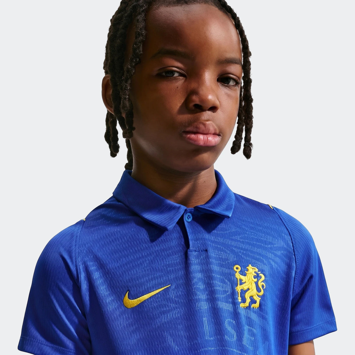 Young boy with dreadlocks wearing a blue Chelsea Fc 2026/27 Stadium Home Big Kids' Nike Dri-Fit Soccer Replica Jersey