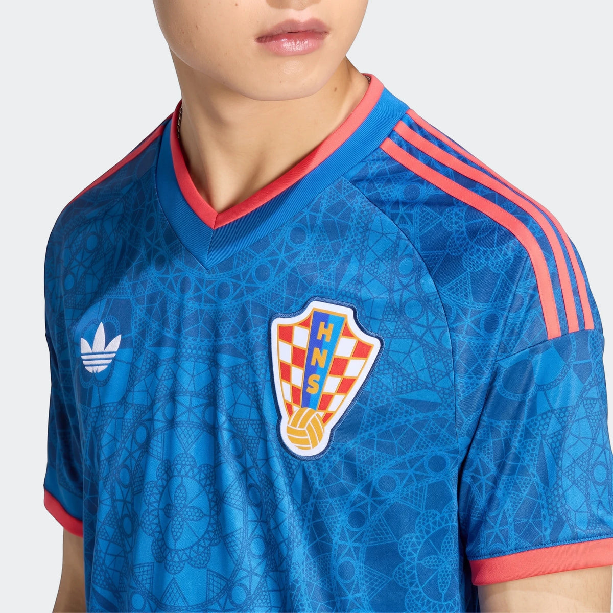 Close-up of a person wearing a blue Adidas Croatia 26 Away Jersey, featuring the team crest and brand logo.
