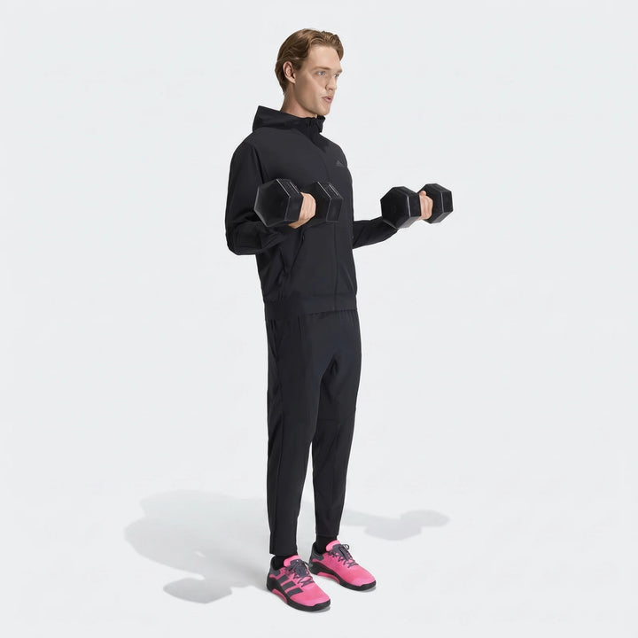 Man wearing a black D4T Hybrid Full-Zip Hoodie, black pants, and pink sneakers, exercising with dumbbells.