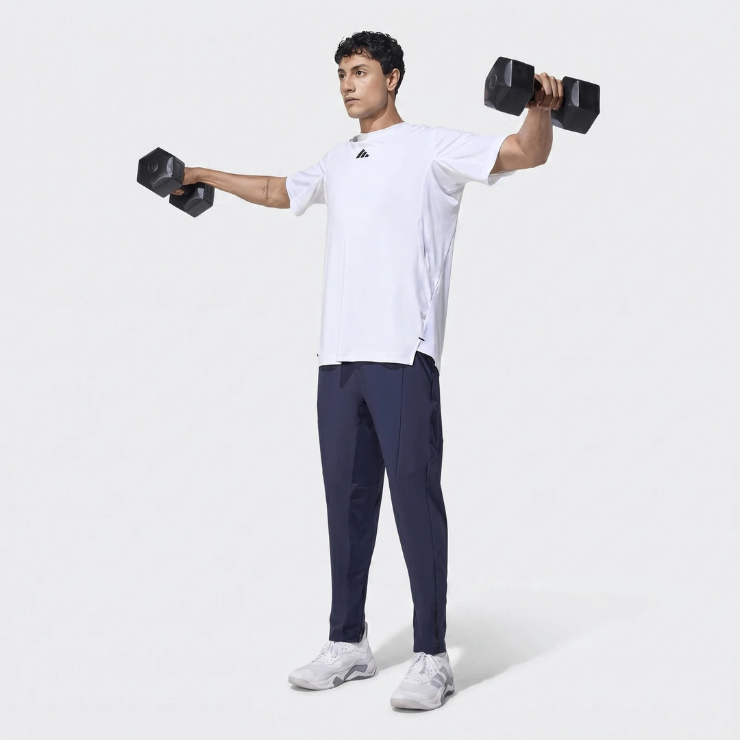 Man in navy D4T Hybrid Pants and white t-shirt exercising with dumbbells, viewed full body.