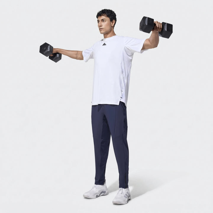 Man in navy D4T Hybrid Pants and white t-shirt exercising with dumbbells, viewed full body.