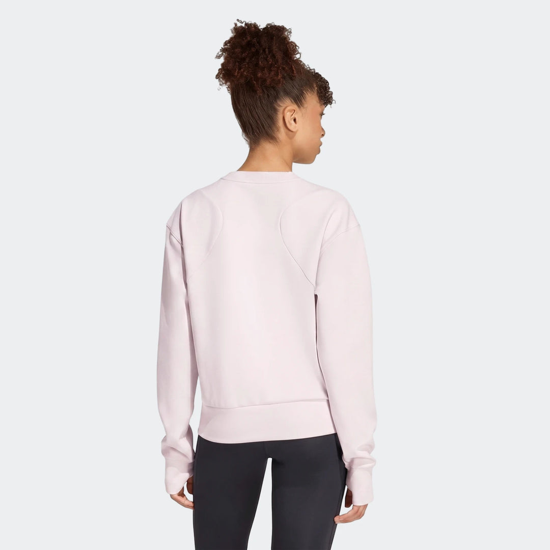 Female model wearing a light pink D4T Knit Crew Sweatshirt and dark leggings, shown from the back view.