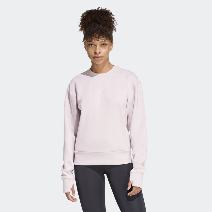 Women's light pink D4T Knit Crew Sweatshirt with subtle Adidas logo, worn by a model in a studio shot.