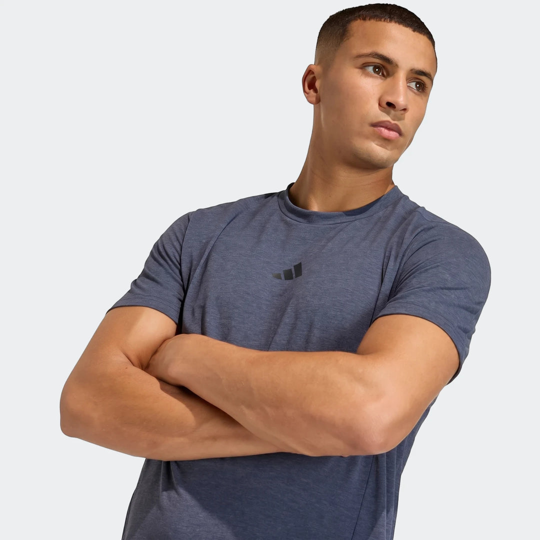 Male model wearing a dark blue D4T short sleeve t-shirt, arms crossed, facing right, studio shot.