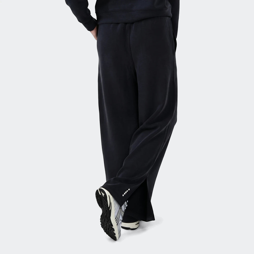 Danielle Trackpant in black with relaxed fit, elastic waistband and tapered leg, shown from the side with sneakers.