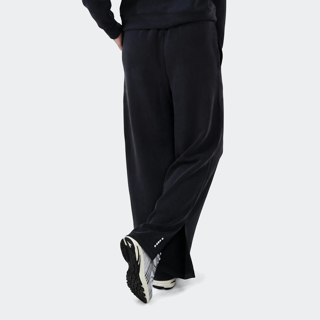 Danielle Trackpant in black with relaxed fit, elastic waistband and tapered leg, shown from the side with sneakers.
