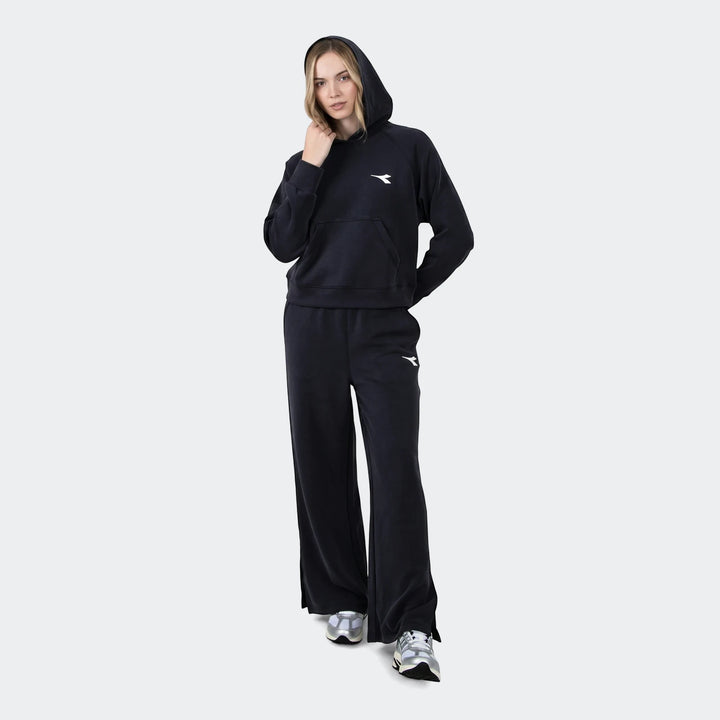 Woman models black Danielle trackpants and matching hoodie, showcasing a comfortable athletic look.