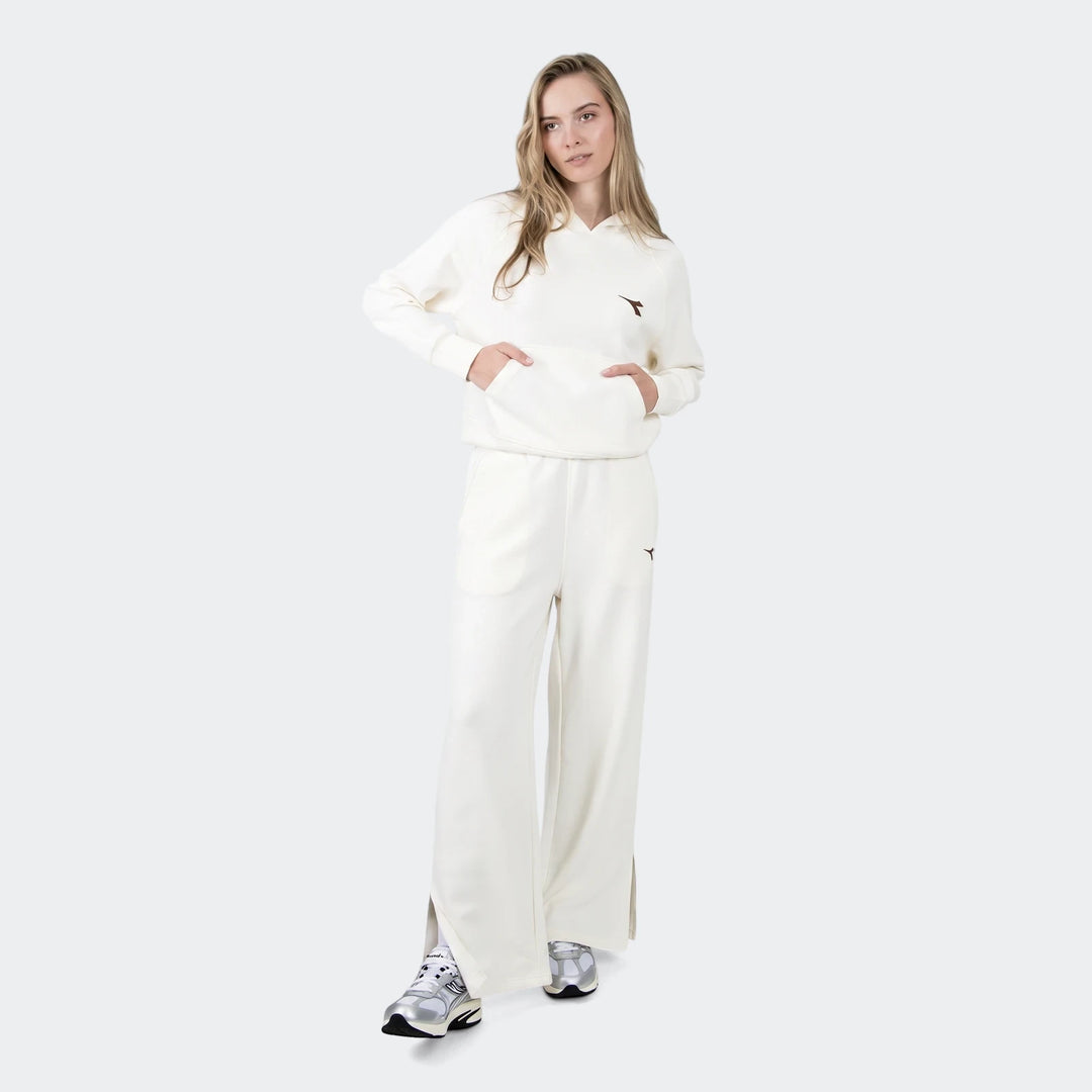 Woman wearing off-white wide-leg Danielle Trackpants and matching hoodie with silver sneakers, full body view.