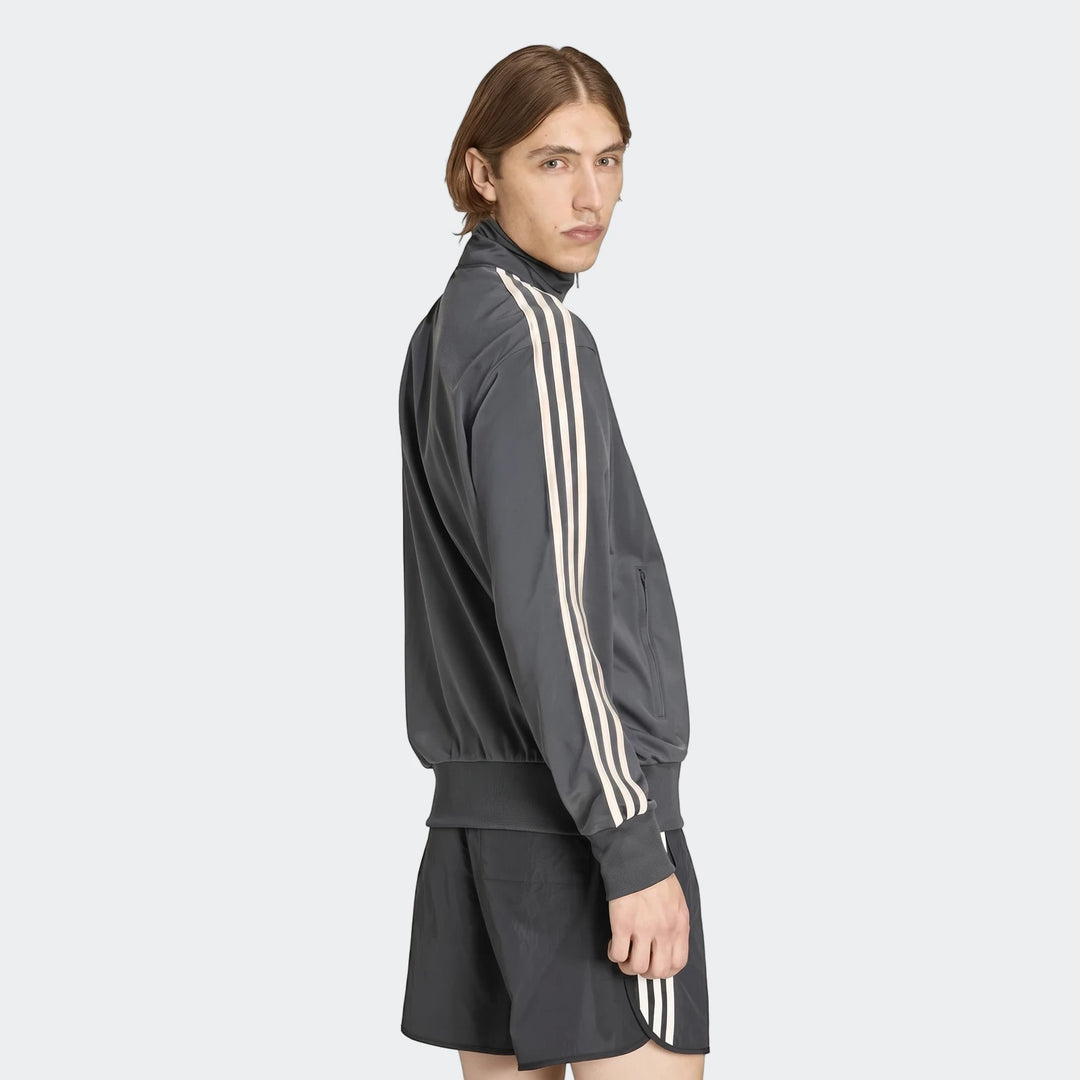 Male model wearing a dark gray Firebird Track Top with beige stripes and matching shorts, photographed from the side.
