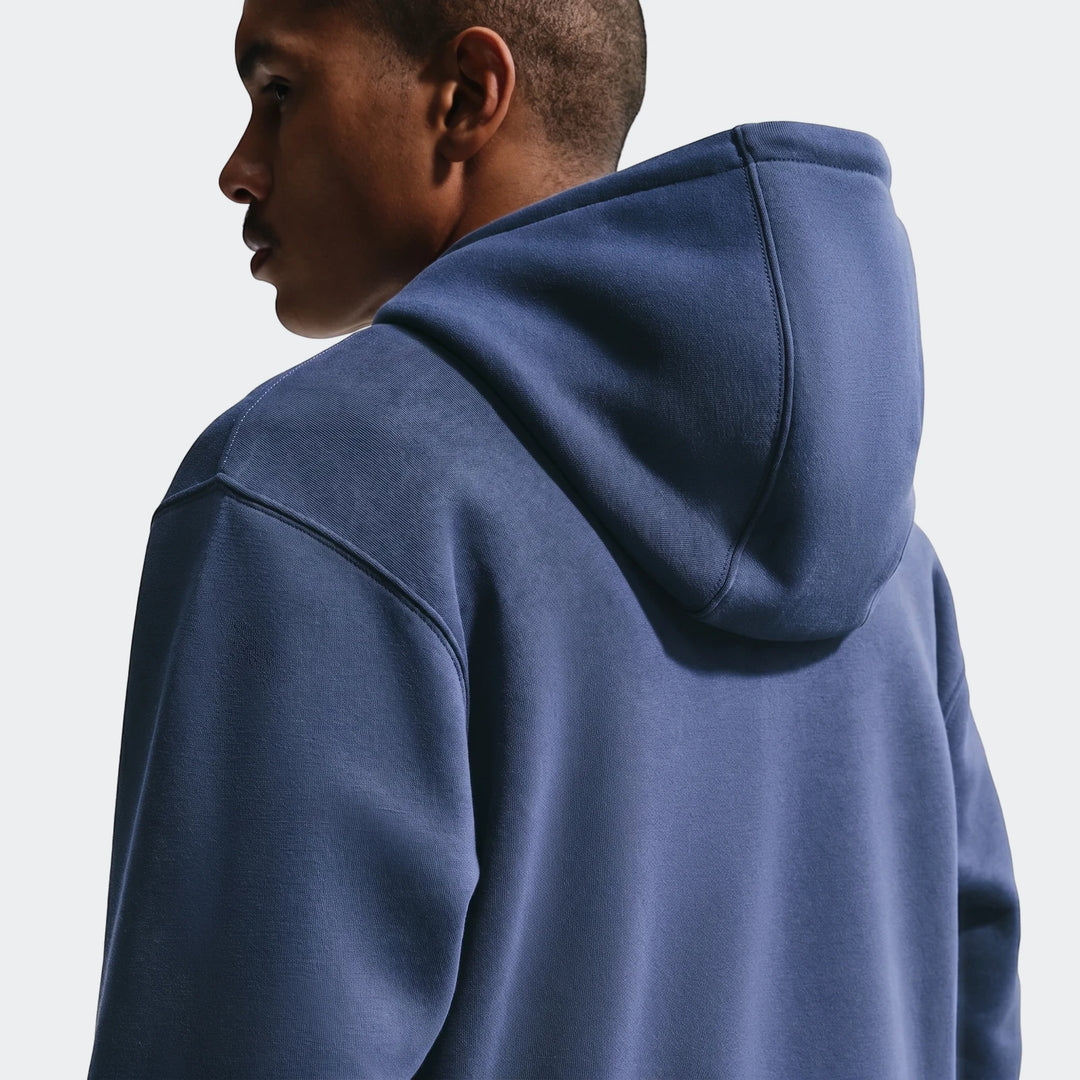 Close-up of a man wearing an England Club blue Men's Nike Soccer Pullover Hoodie, viewed from the back and right profile.